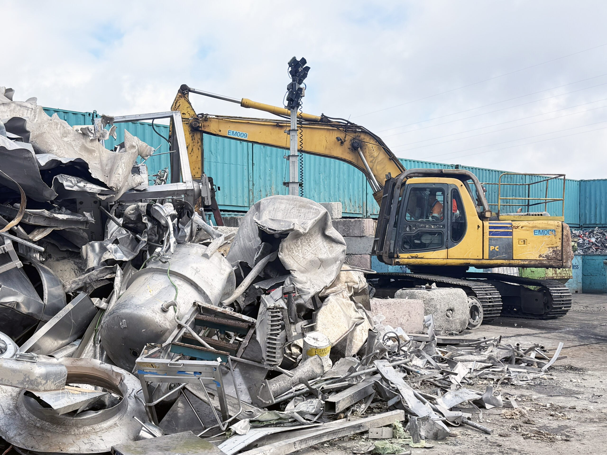 IMG_0158 Scrap metal piled beside an excavator at a metal recycling facility.